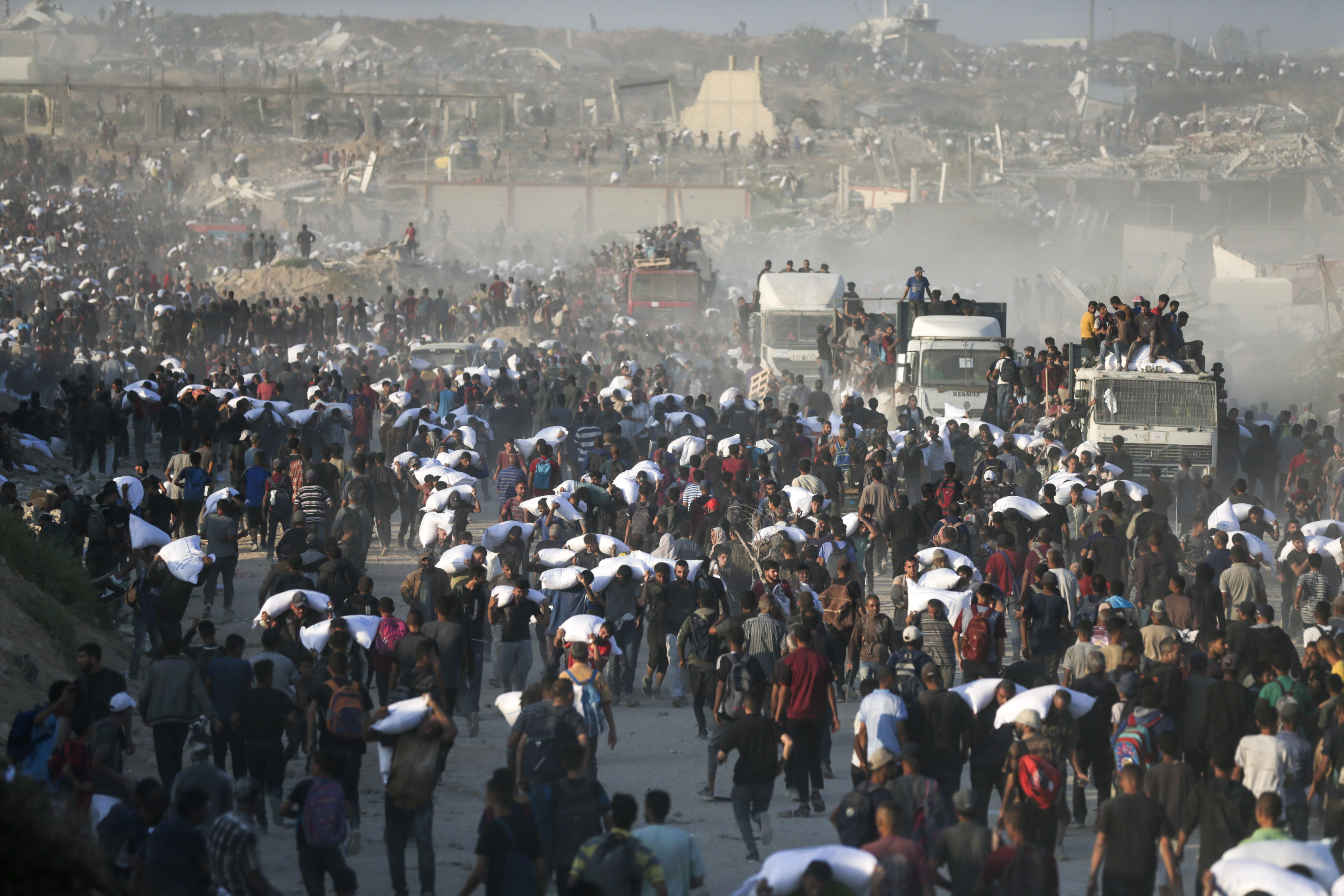 פלסטינים אוספים סיוע הומניטרי ממשאיות, צפון העיר עזה, יוני 2025